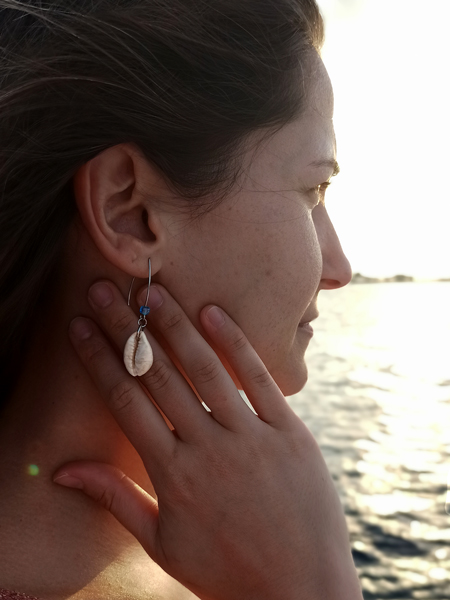 Jeune femme regardant l'horizon, avec une boucle d'oreille coquillage cauri